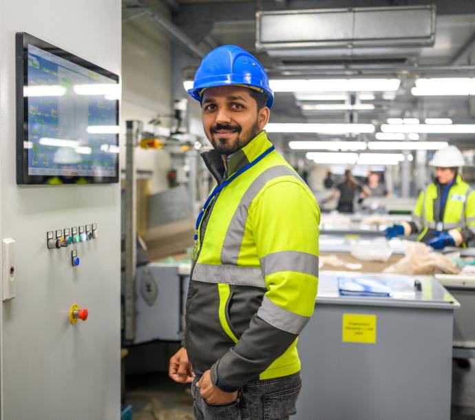 Mann in Warnweste und Helm in Industriehalle