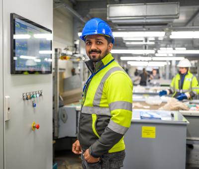 Mann in Warnweste und Helm in Industriehalle